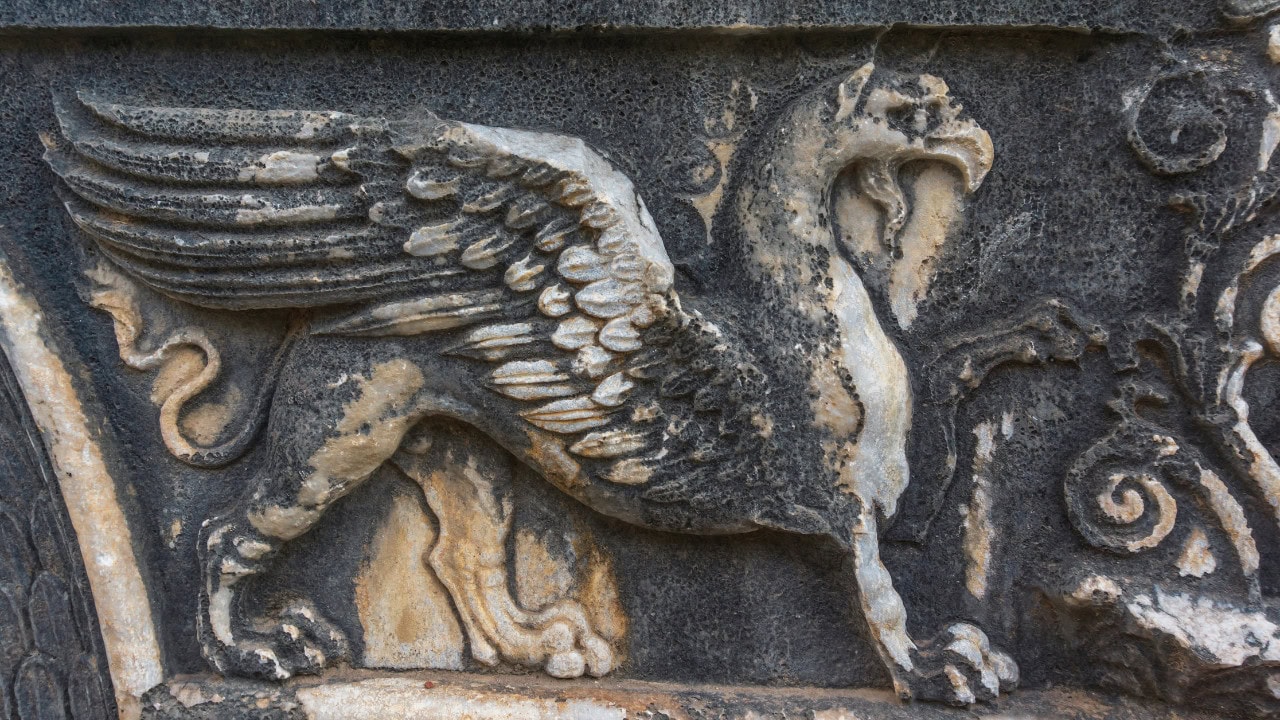 Stone relief carving of a griffin with spread wings.