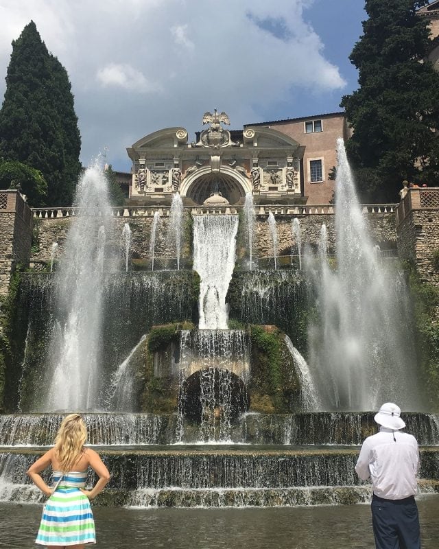 Two people stand before the large, tiered Fountain of Neptune at Villa d’Este.