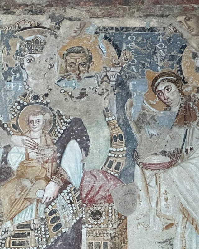 Fragmented medieval fresco depicting a crowned figure holding the Christ child, with an adult male and a third figure to the right.