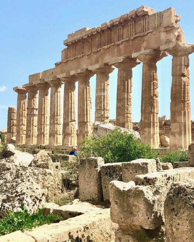 A row of tall, ancient stone columns at the Selinunte archaeological site in Sicily.