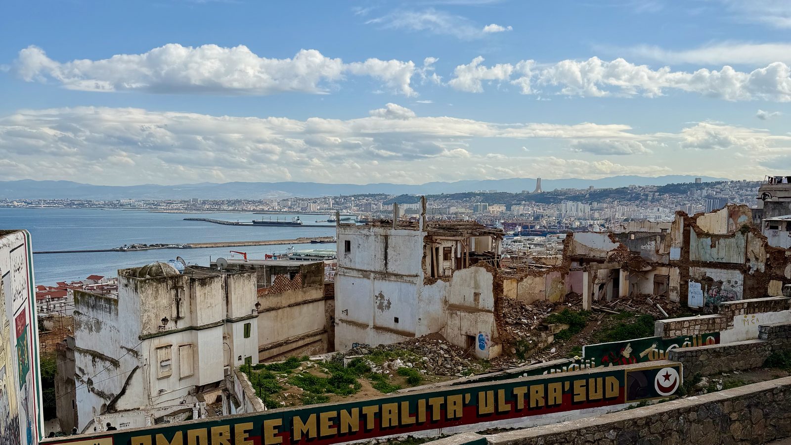 Ruined white buildings overlooking the Mediterranean Sea and the city of Algiers.
