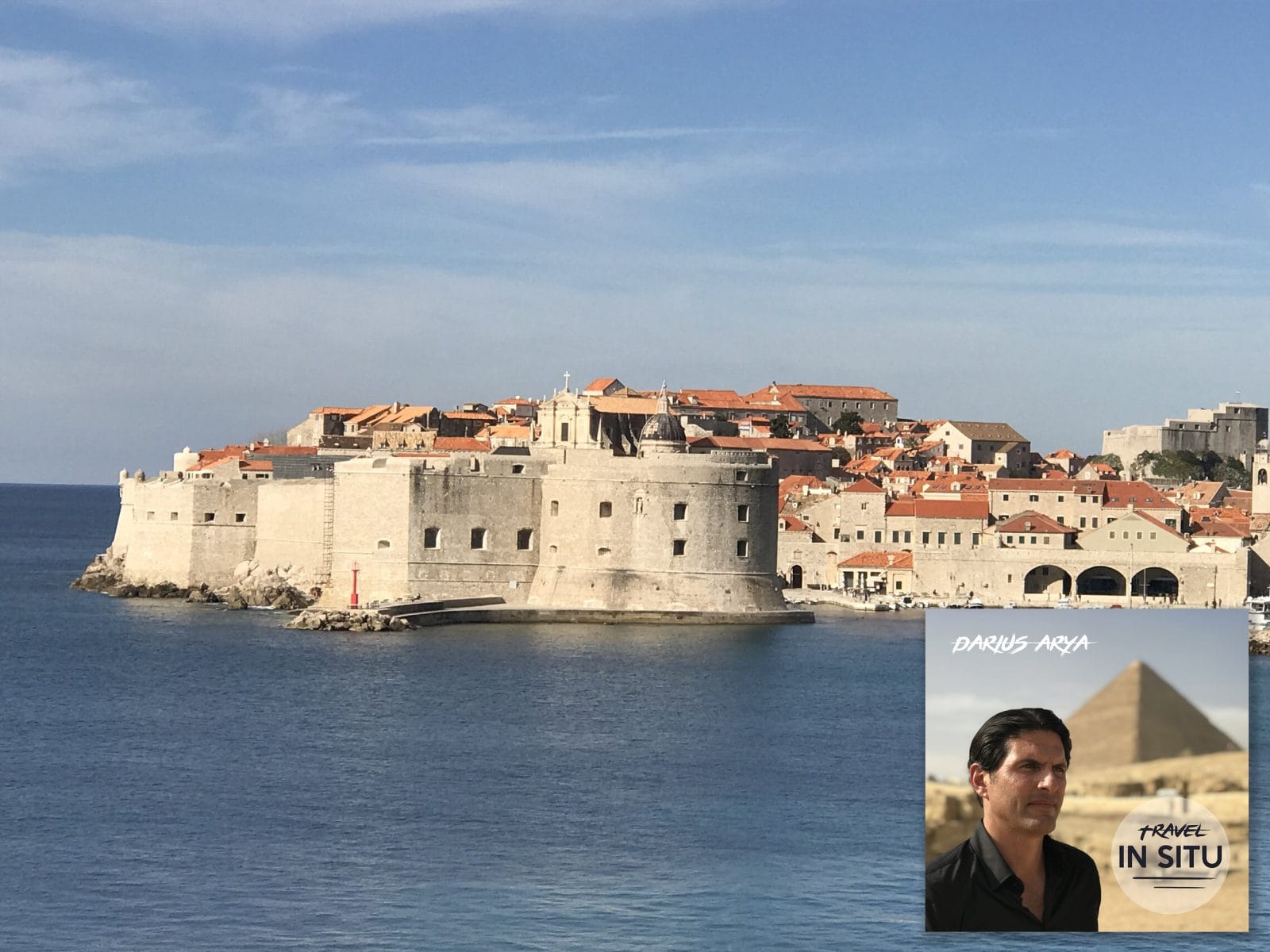 View of Dubrovnik’s old city walls along the Adriatic Sea under a clear sky; an inset shows a man and “Travel In Situ” podcast cover with a pyramid in the background.
