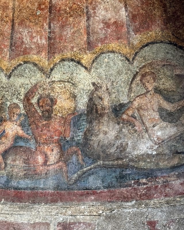 Ancient fresco depicting a centaur and a person riding a sea horse.