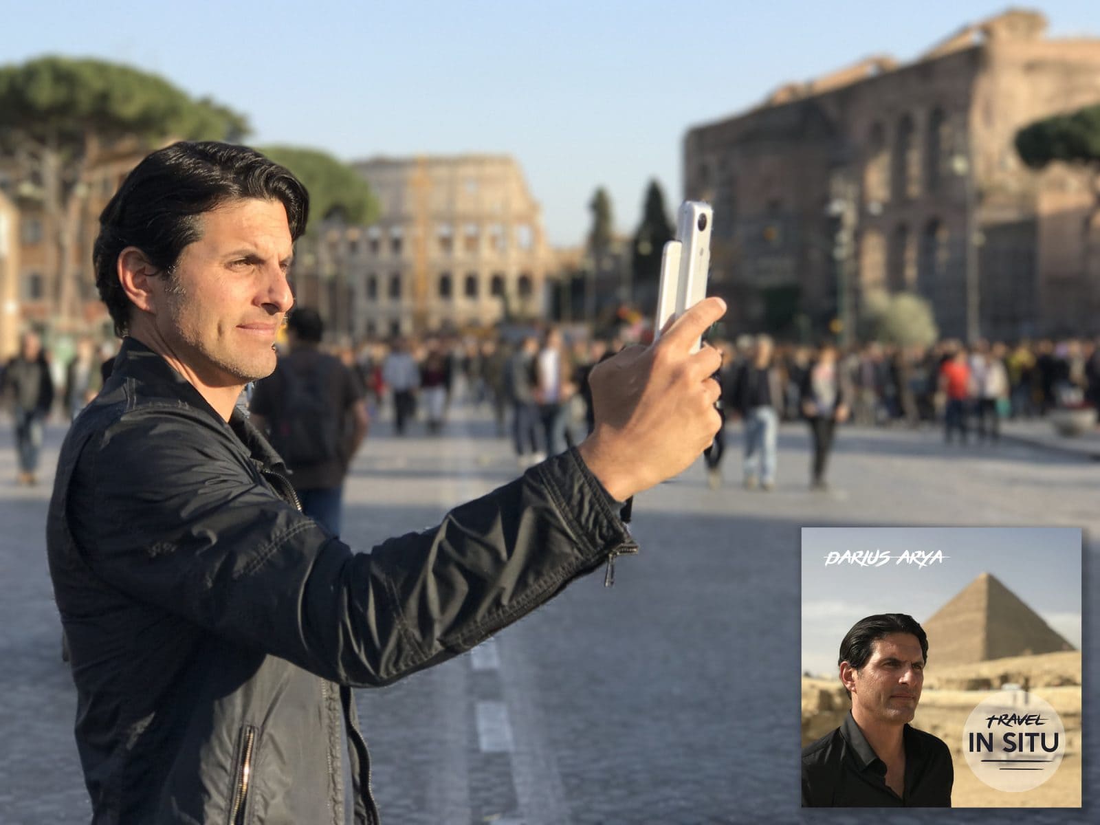A man in a black jacket takes a selfie near the Colosseum in Rome, with crowds behind him. An inset shows a promotional image for “Travel In Situ” by Darius Arya.