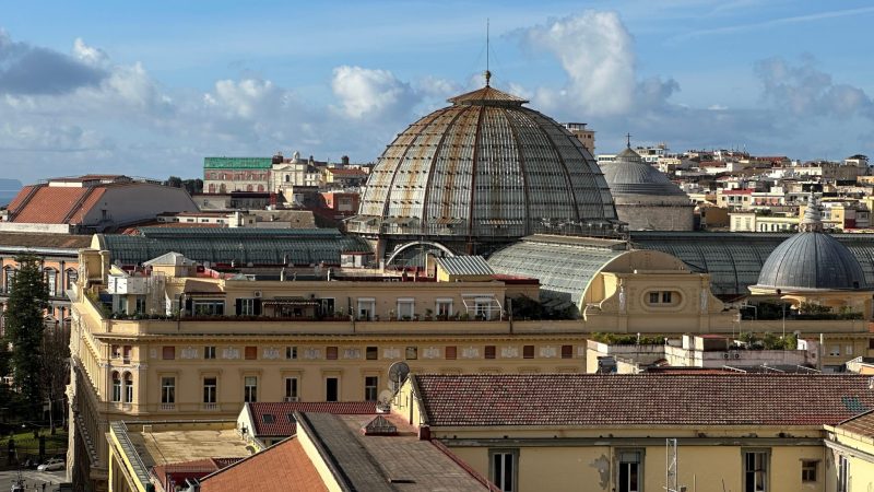 Aerial view of the Naples city skyline featuring the large glass dome of the Galleria Umberto I.
