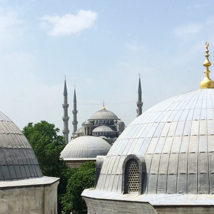 View of the Blue Mosque and its minarets framed by the domes of another structure.