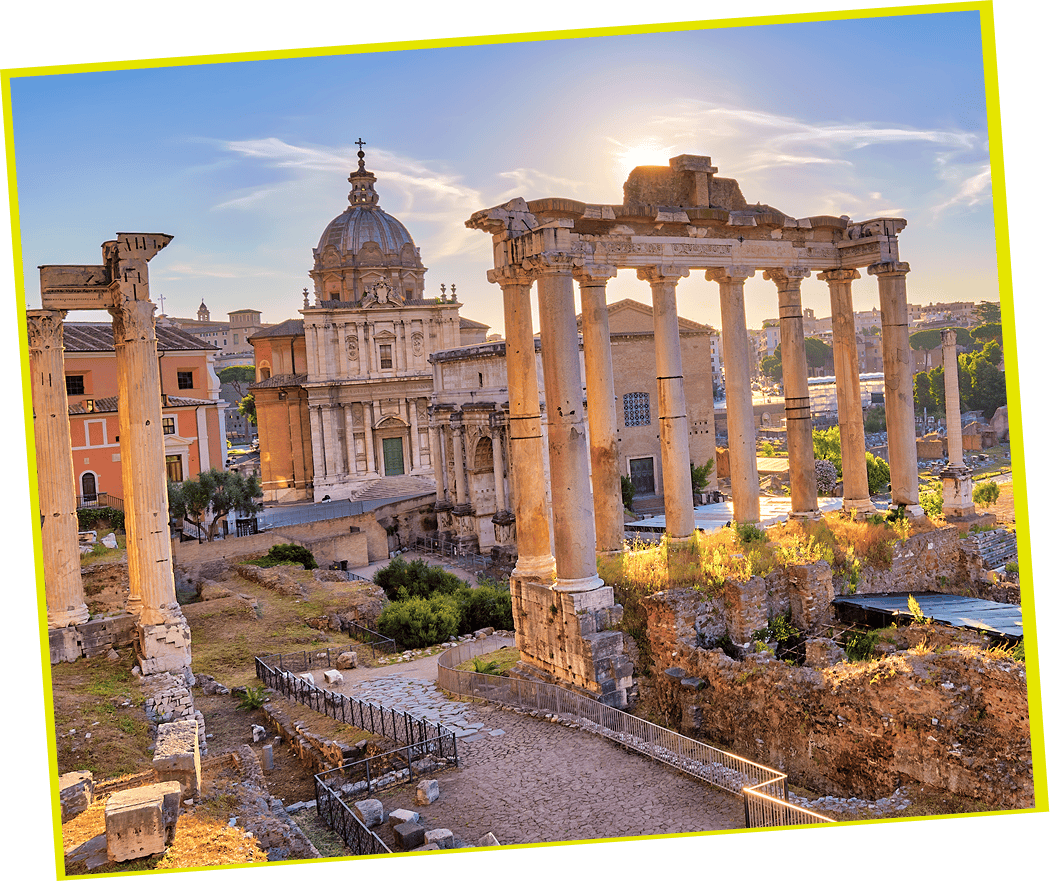Ancient Roman ruins with tall columns and historic buildings at sunset, likely the Roman Forum in Rome, Italy.